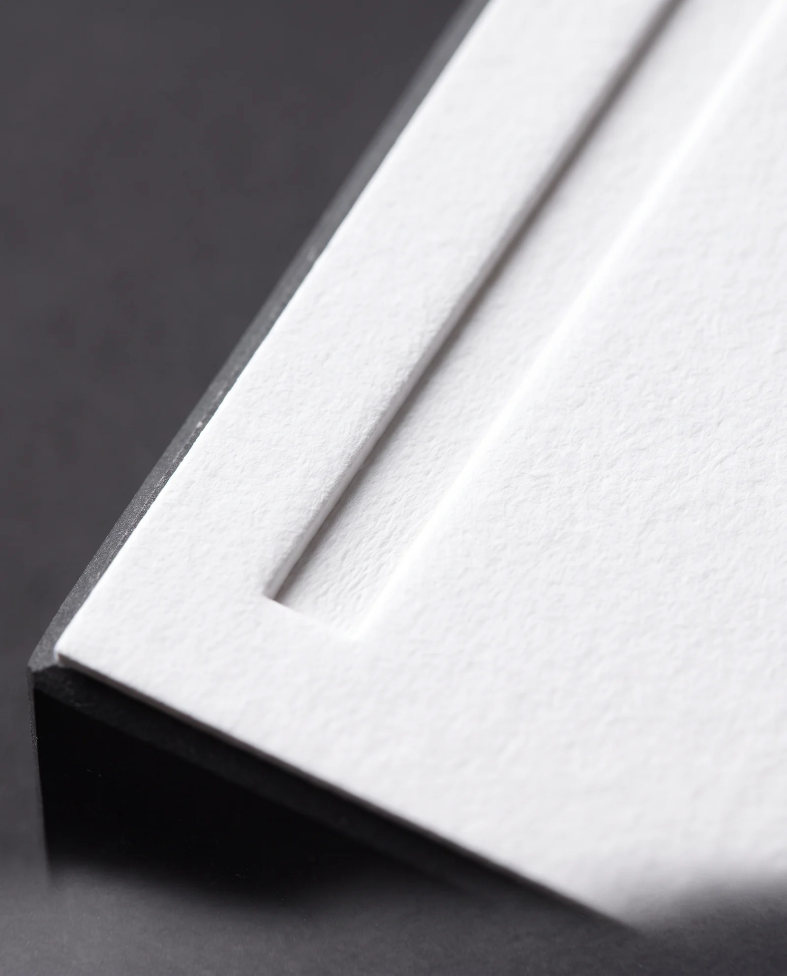 Macro of a blind-debossed line, its walls crisp and fibres compressed.