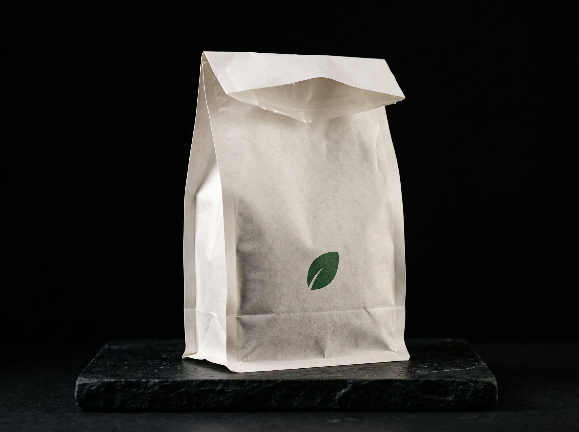 A white kraft compostable pouch with a small green leaf print and no metallic layer.