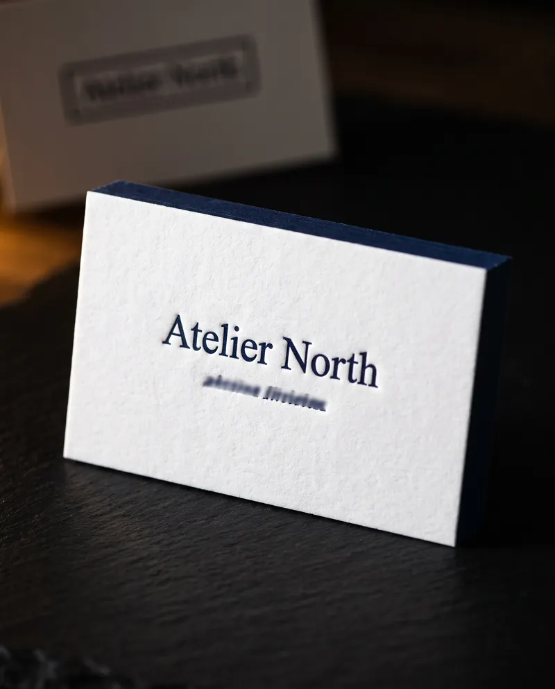 White cotton signing agent business card with navy letterpress name and navy painted edge