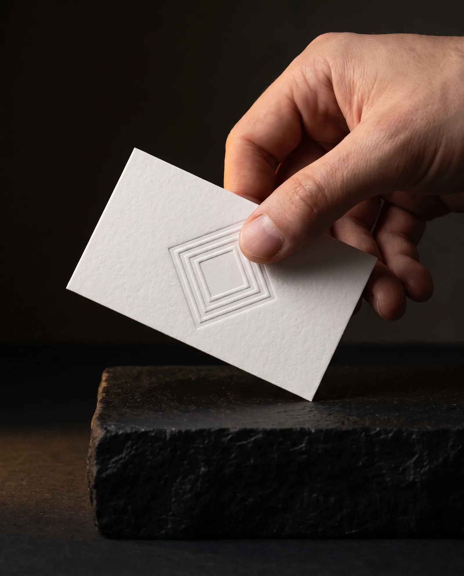 Thumb crossing a blind embossed mark on a thick white cotton business card