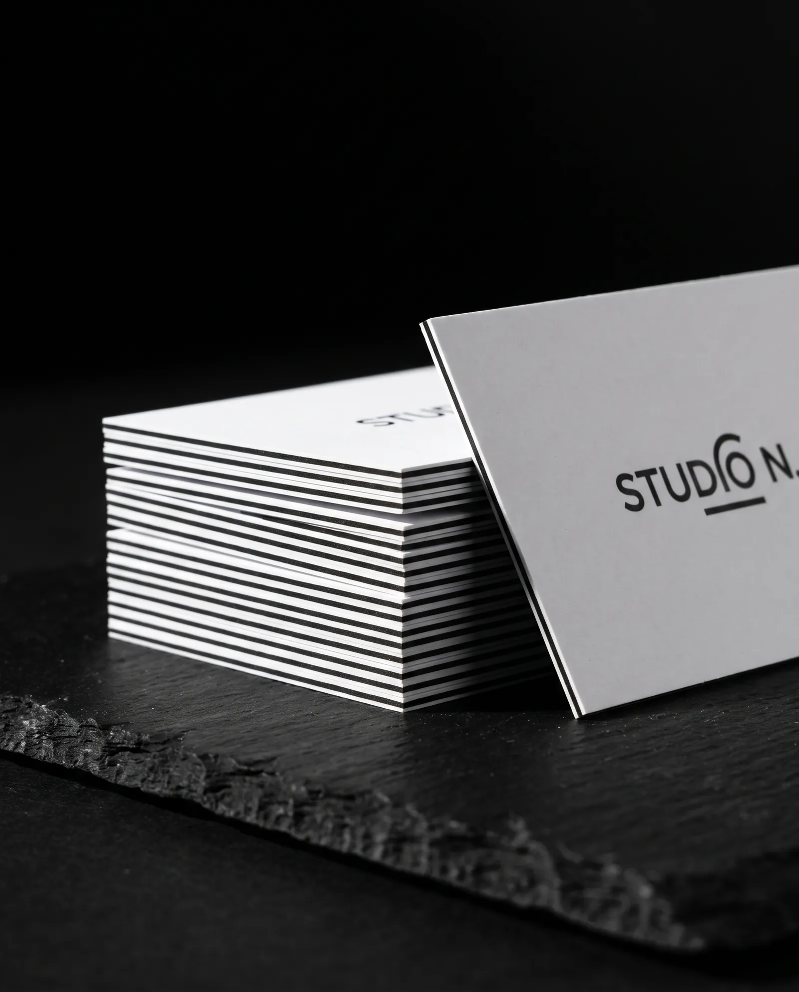 Stack of white triplex business cards showing a black core layer on the edge