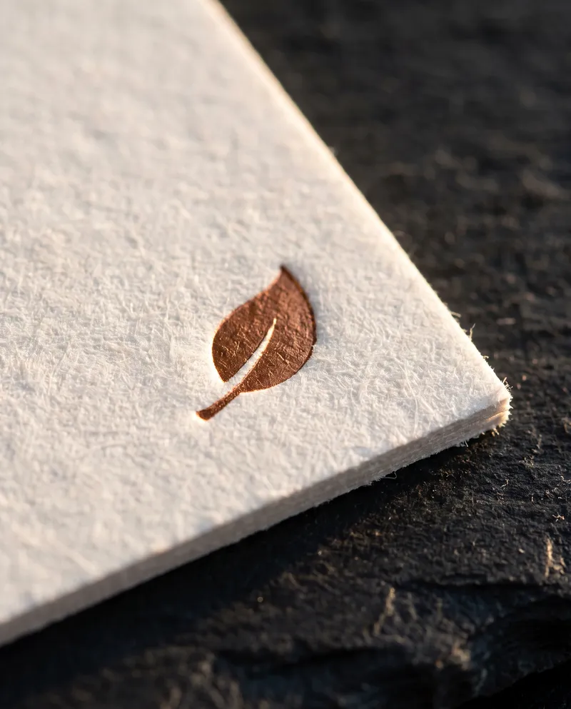 Close-up of a solid copper foil mark pressed into white 32pt cotton on a mini business card