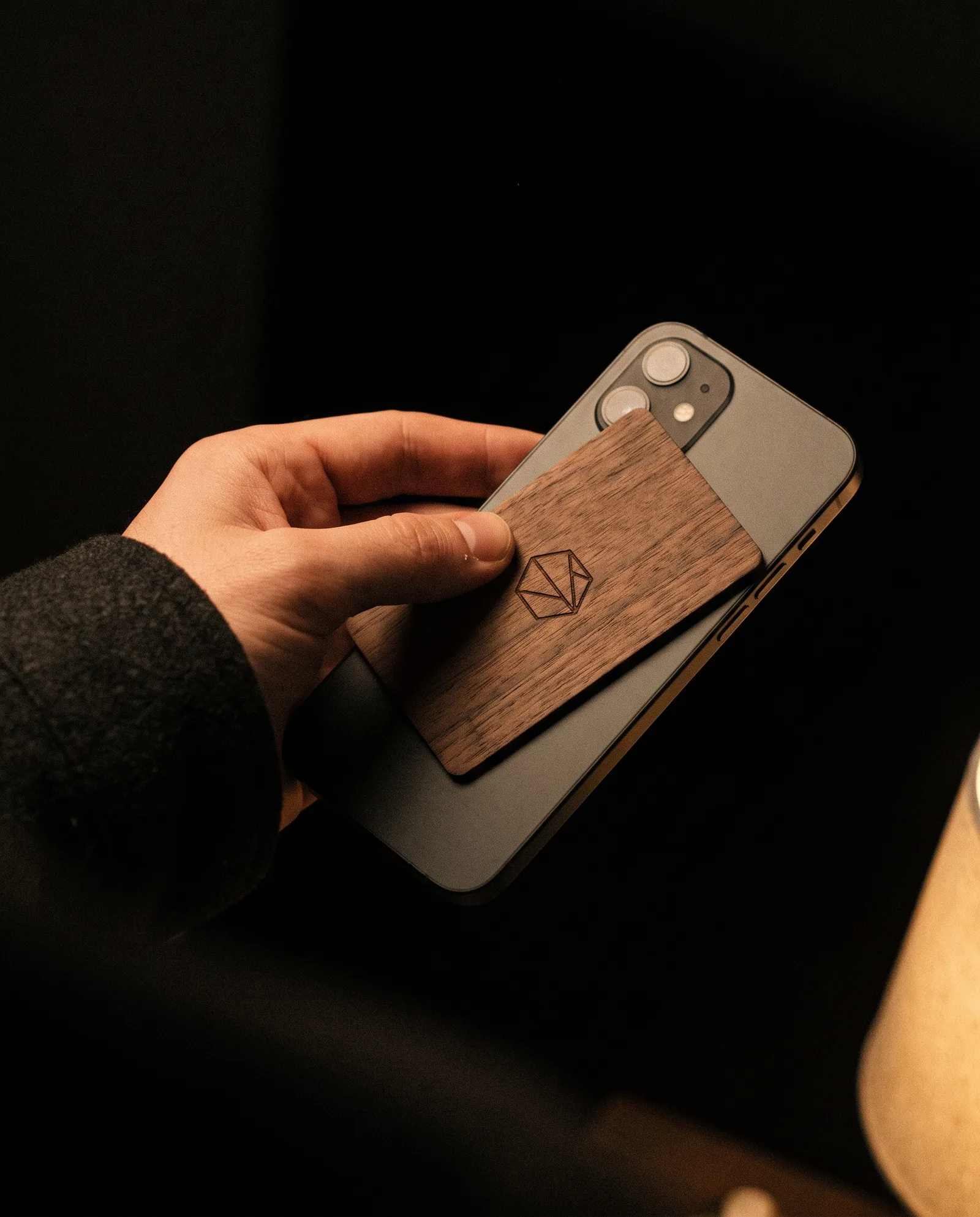 Hand tapping a walnut NFC card to the back of a phone