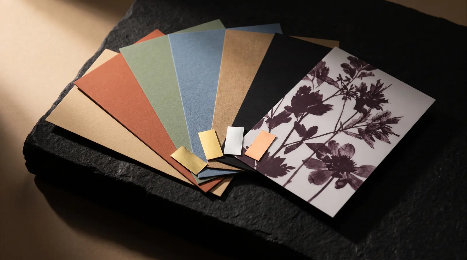 Fan of coloured, kraft and black uncoated wraps, soft-touch sheet and three foil chips