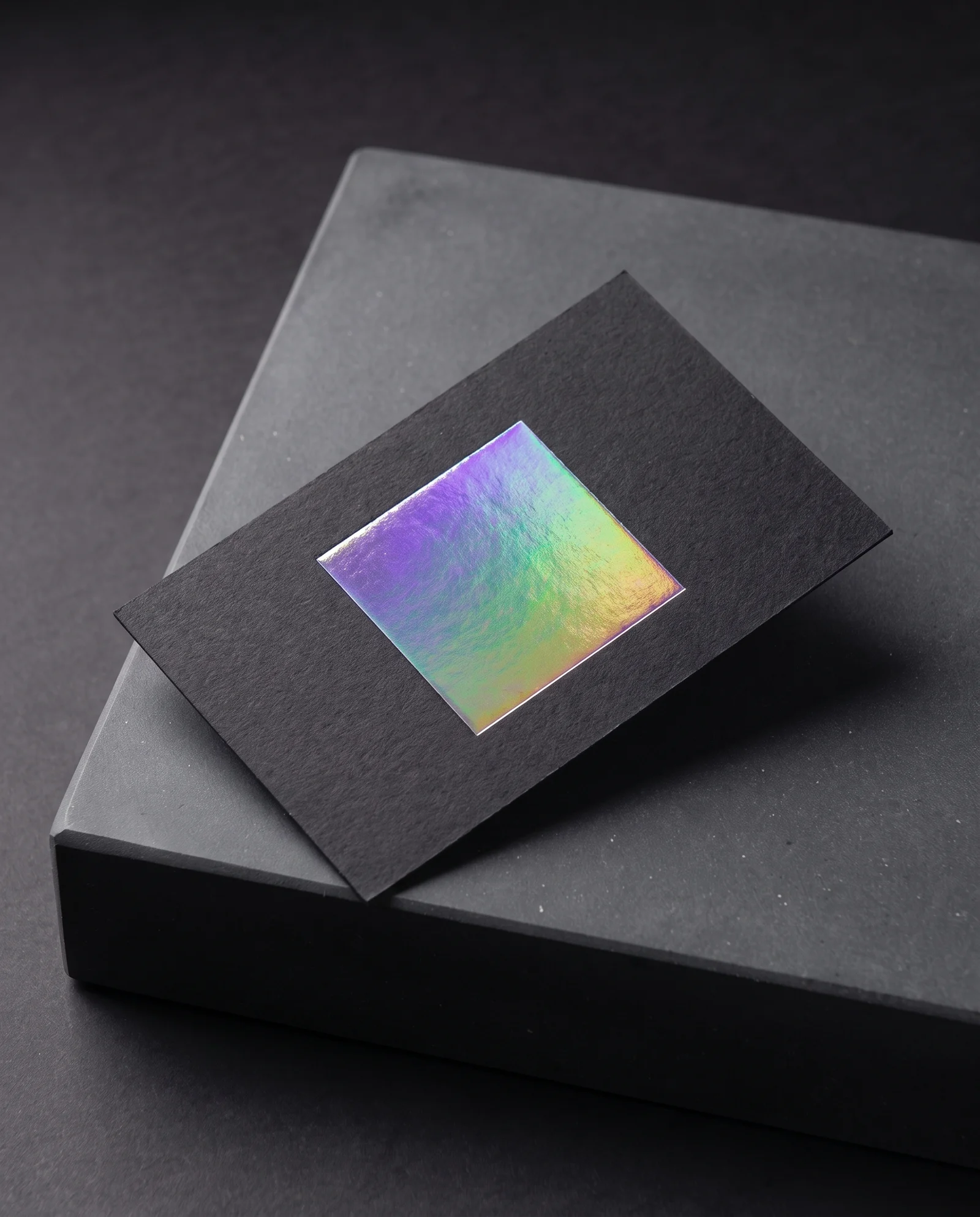 Holographic foil on black cotton, shifting colour across its surface.