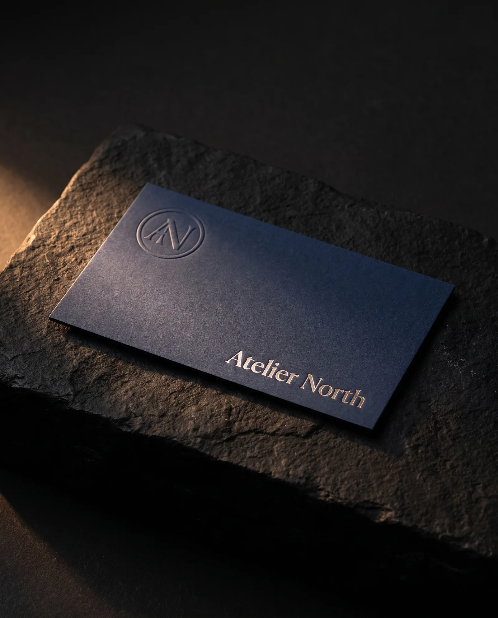 Navy business card with a blind embossed mark and a name in silver foil