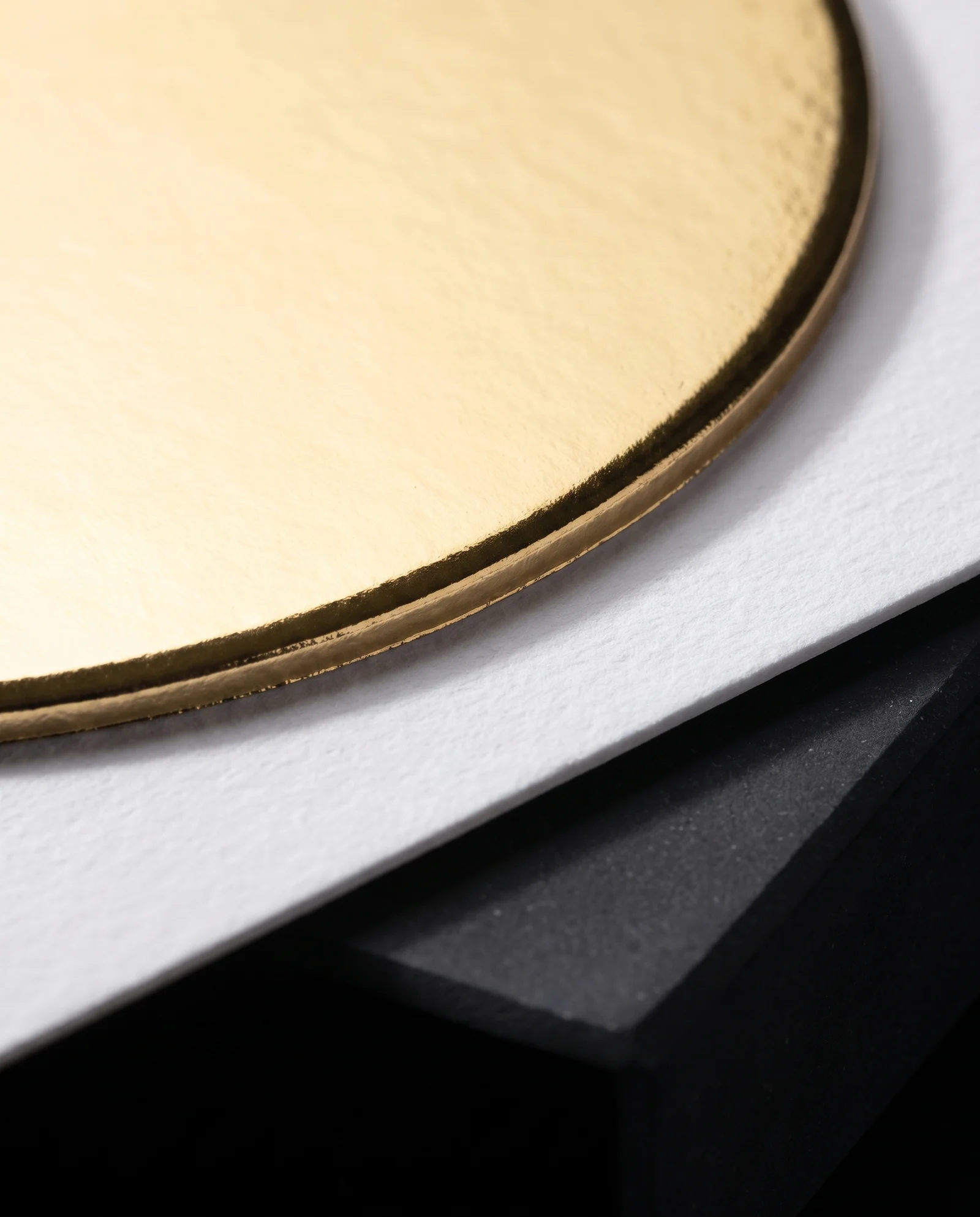 Macro of gold foil ending exactly at the raised shoulder of the emboss.