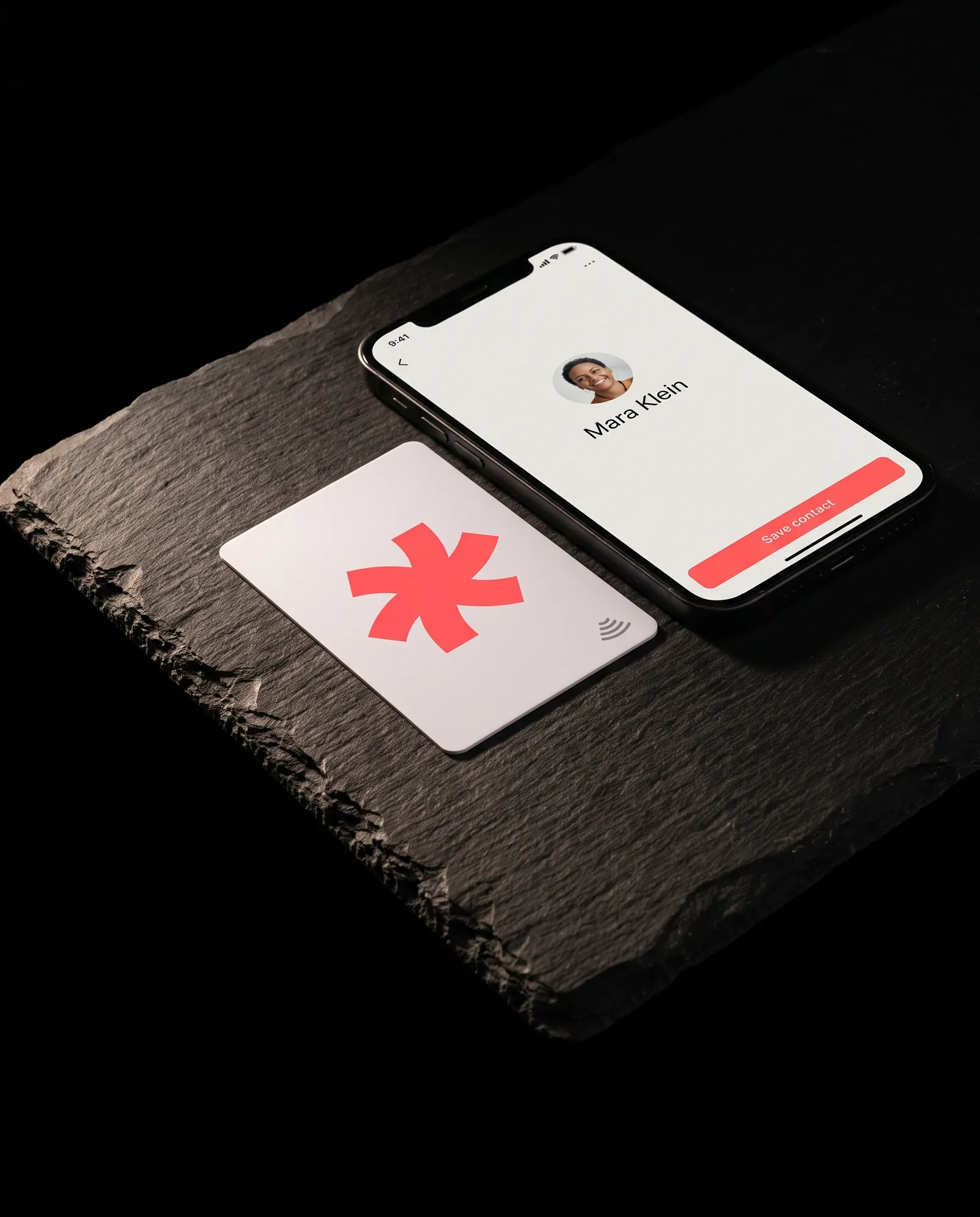 White plastic NFC business card with a coral Print Peppermint mark beside a phone showing the contact page it opens, on black slate