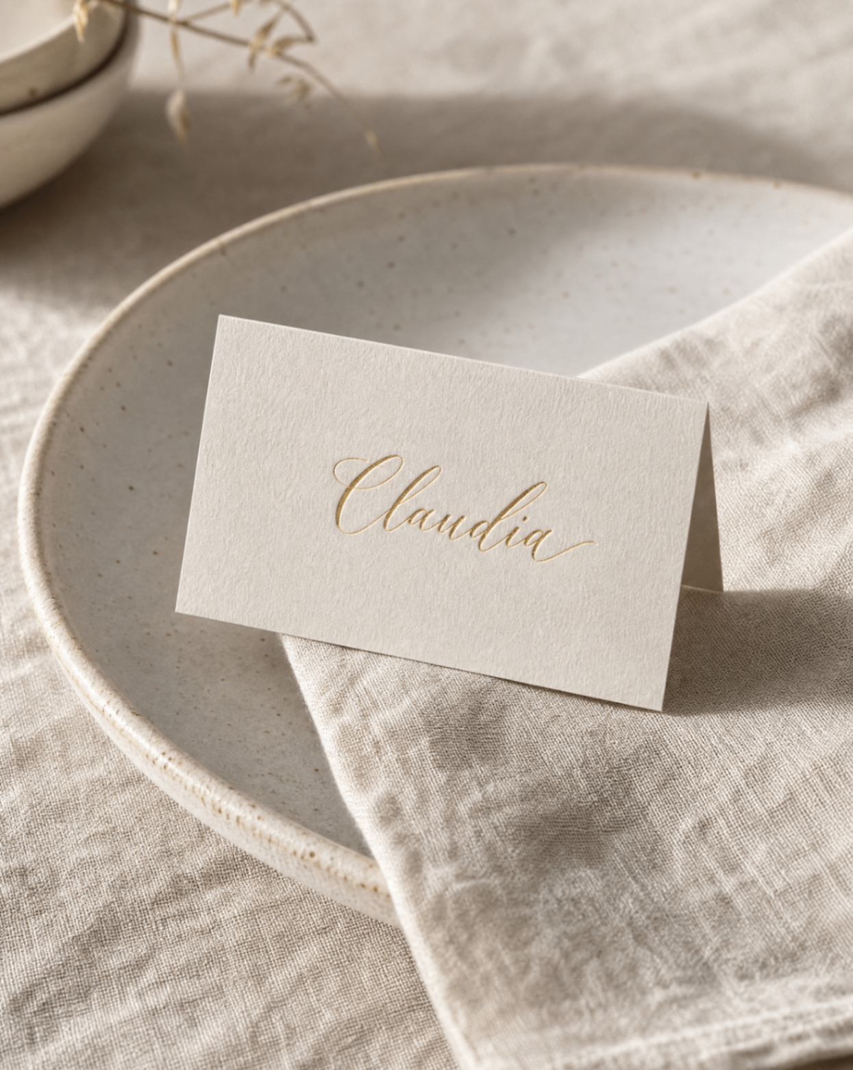Place Cards Folded cotton place card with a foil-stamped guest name and painted edge, standing on a dark table setting.