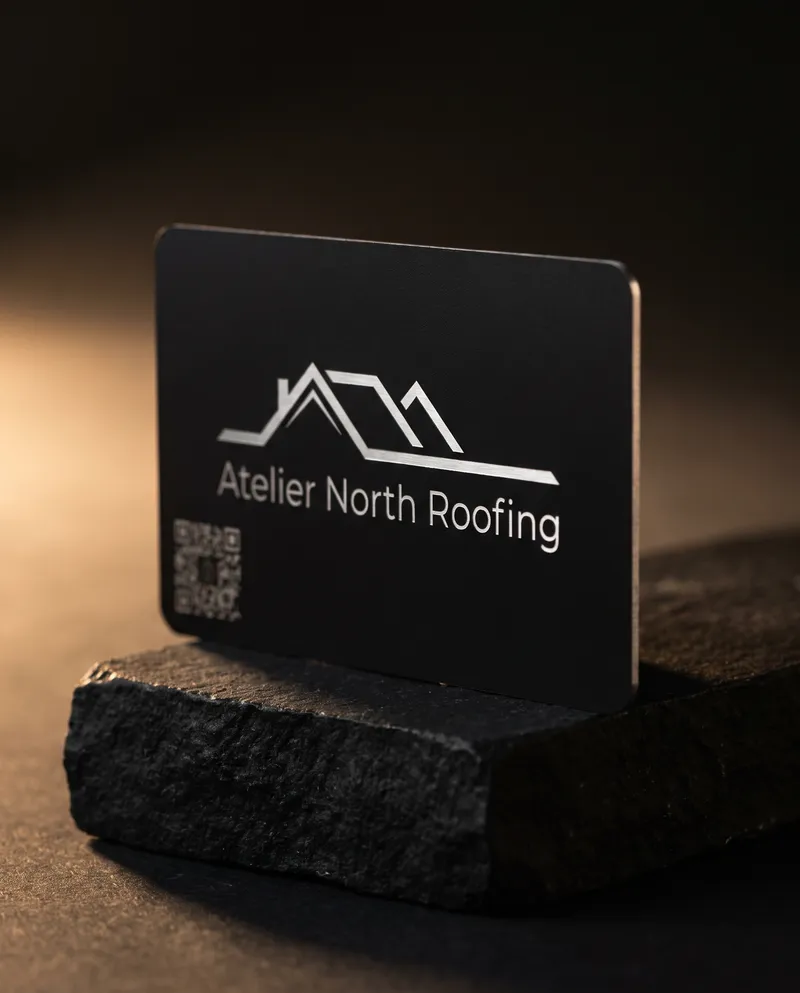 Matte black stainless steel business card laser engraved with a roofline mark on black stone
