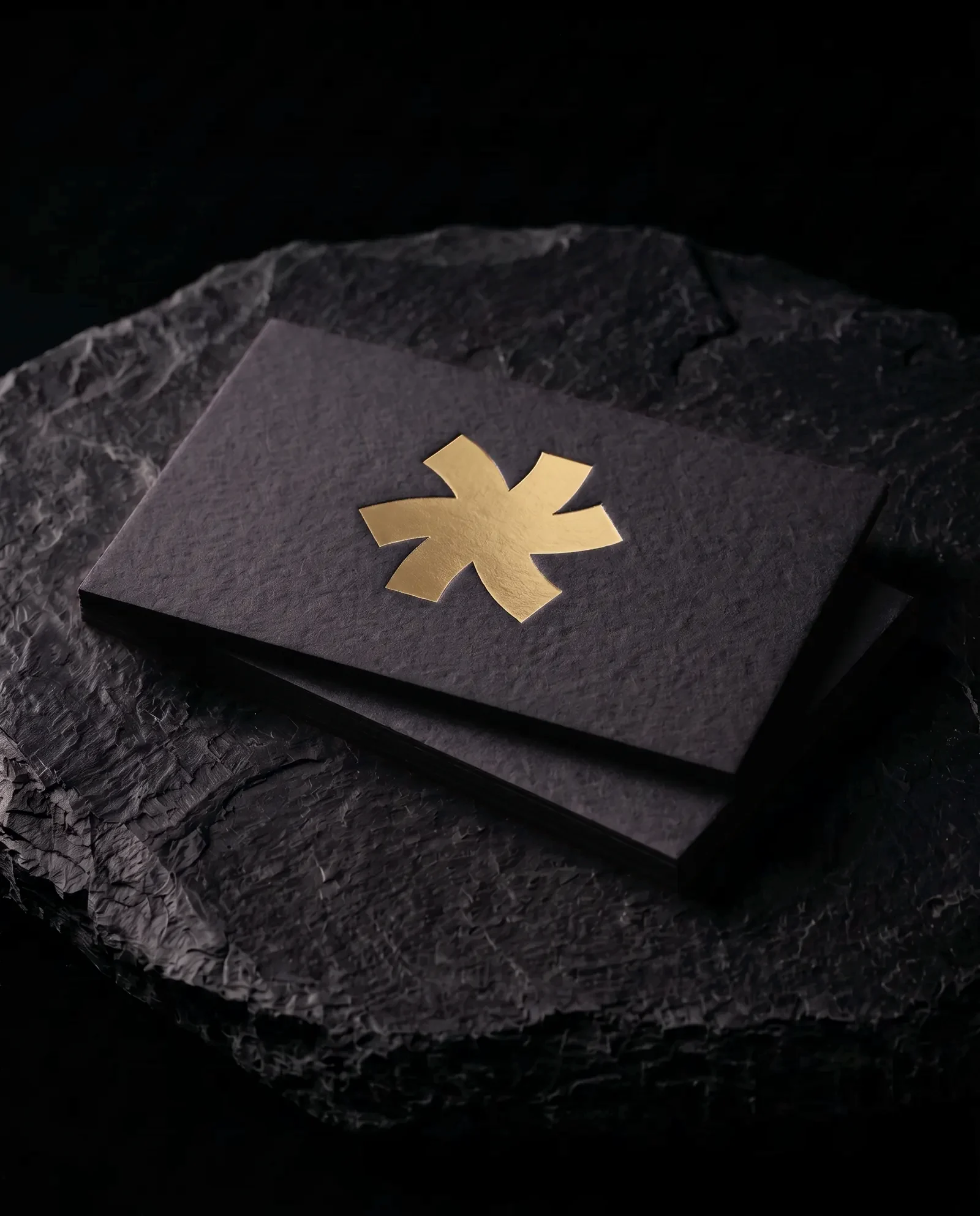 Gold hot foil business card on black stock: the Print Peppermint mark stamped in gold foil, on a black slate plinth