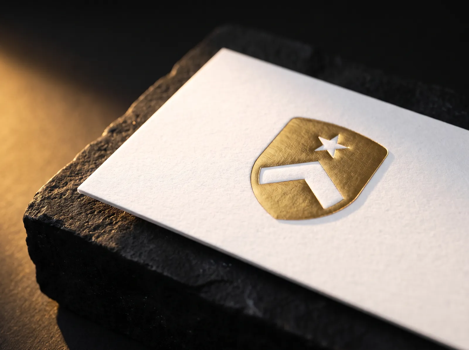 Gold foil embossed business card, the foiled logo raised on white cotton, side light