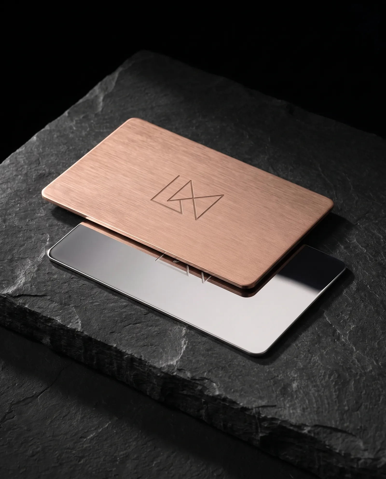 Brushed rose gold metal business card resting on a mirror-polished silver stainless card