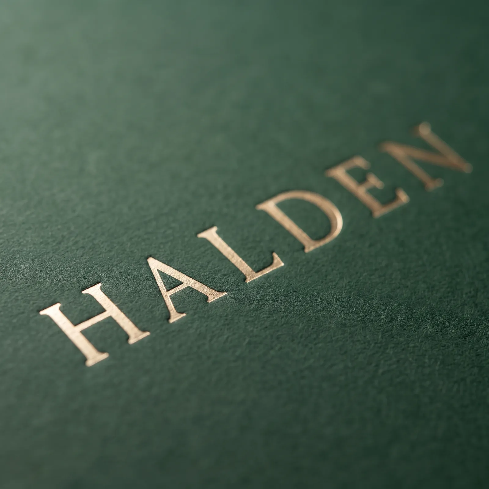 Macro of gold hot foil letters pressed into green uncoated paper