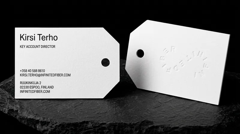 Swing-tag-shaped business card in white recycled cotton with a red core showing at the edge and the hole