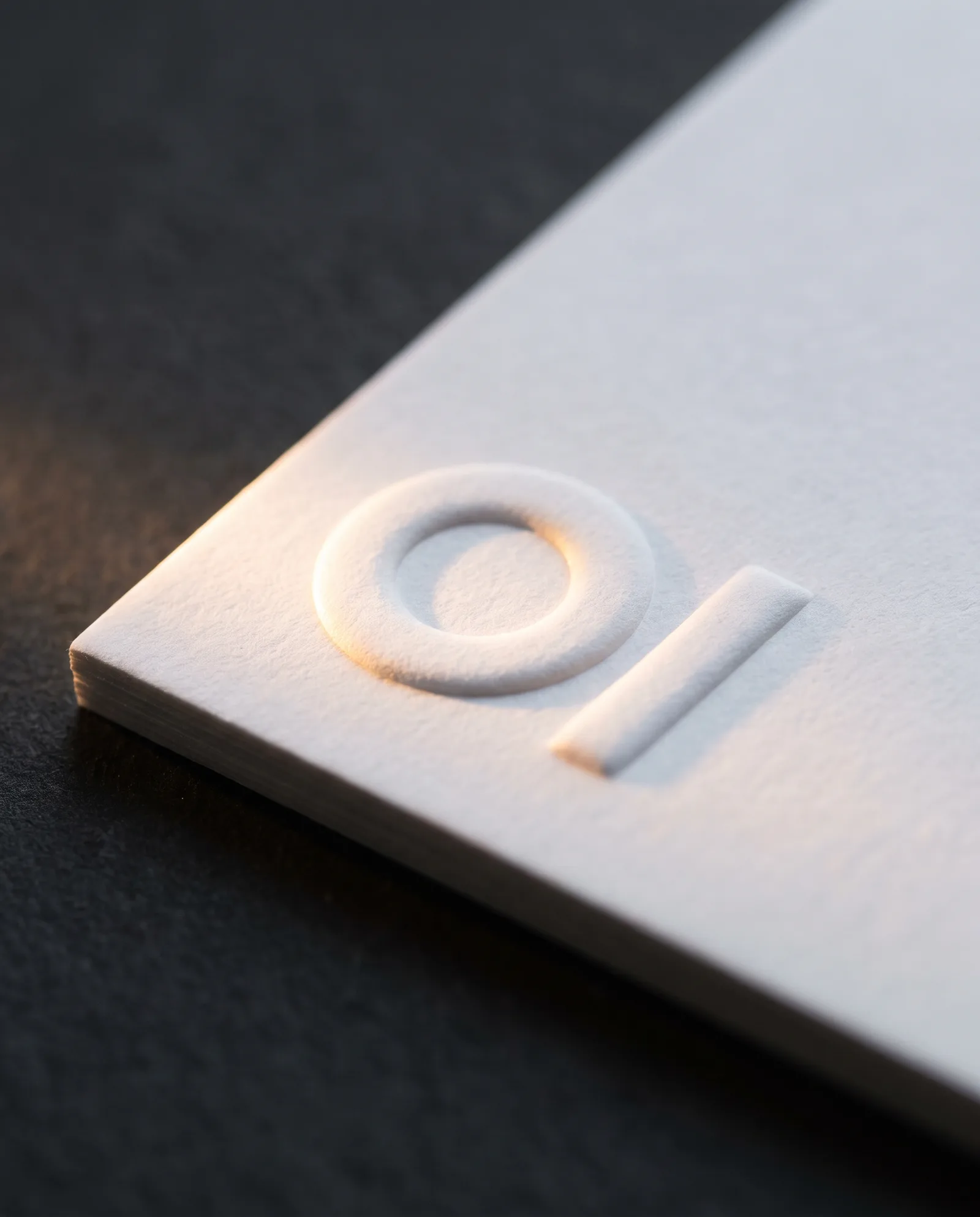 Macro of custom embossing on business cards: cotton fibres stretched over the raised edge of a blind embossed mark