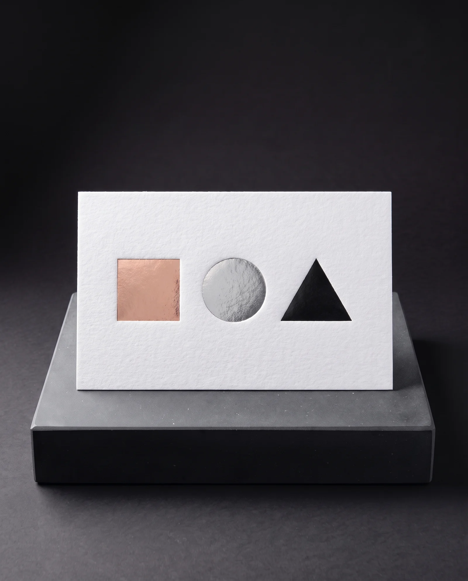 Rose gold, silver and matte black foil shapes on one white cotton card.