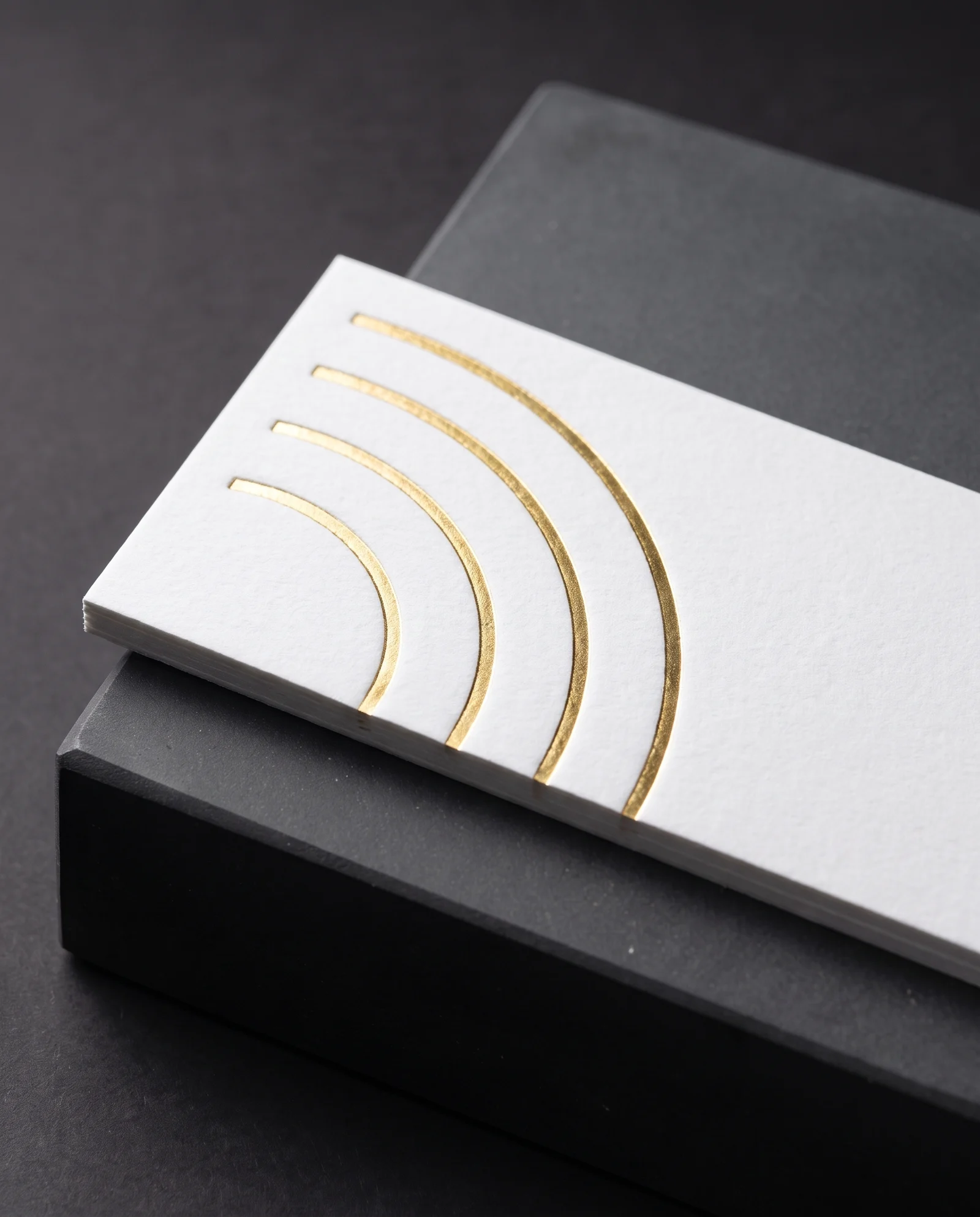 Gold hot foil pressed into white cotton, the impression visible around each line.