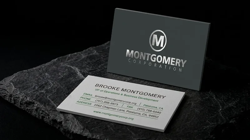 Construction services business card with a brushed silver foil badge on charcoal, like a machined nameplate