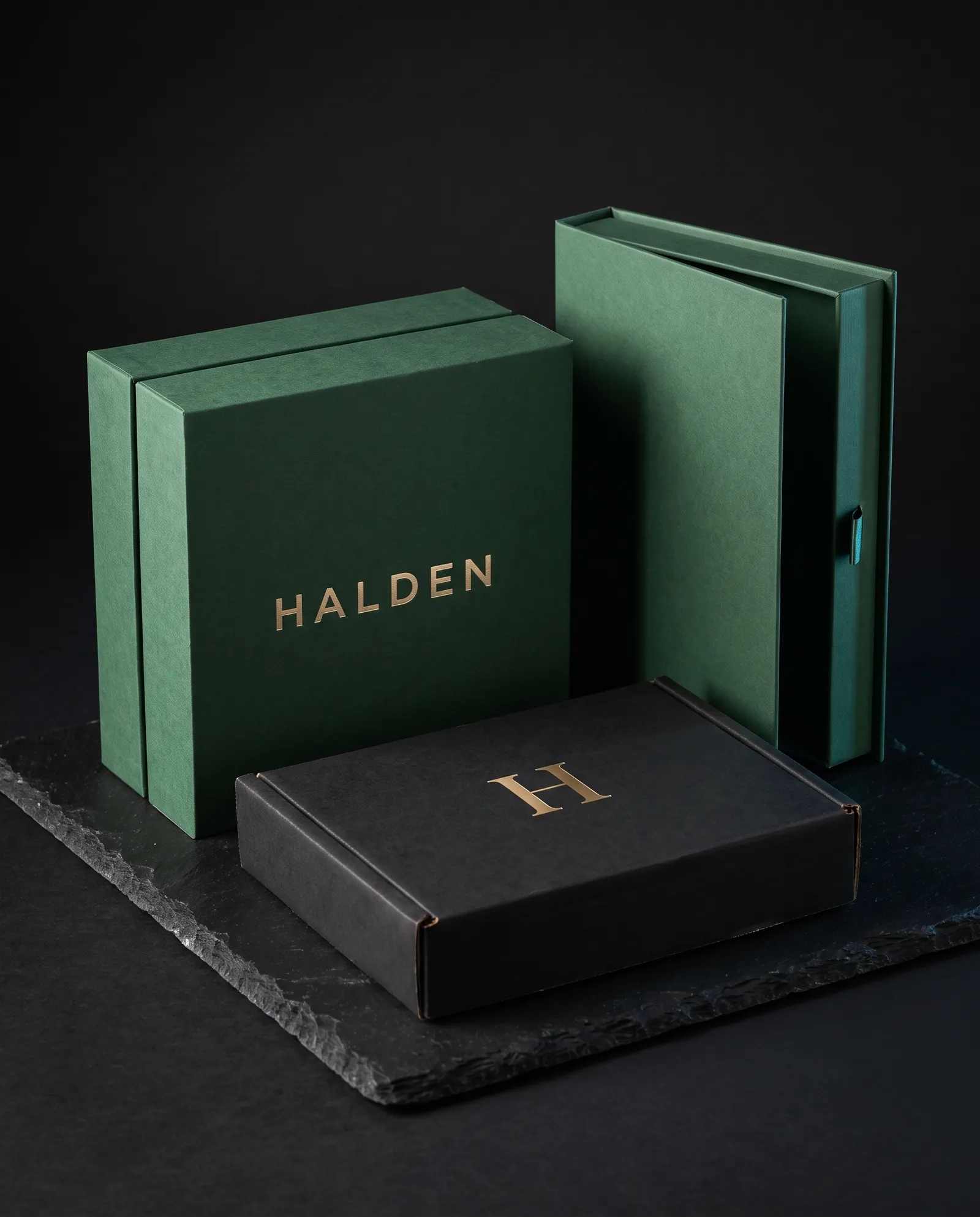 Three box structures from one brand: a rigid box, a book-style magnetic box and a black mailer, each with gold foil