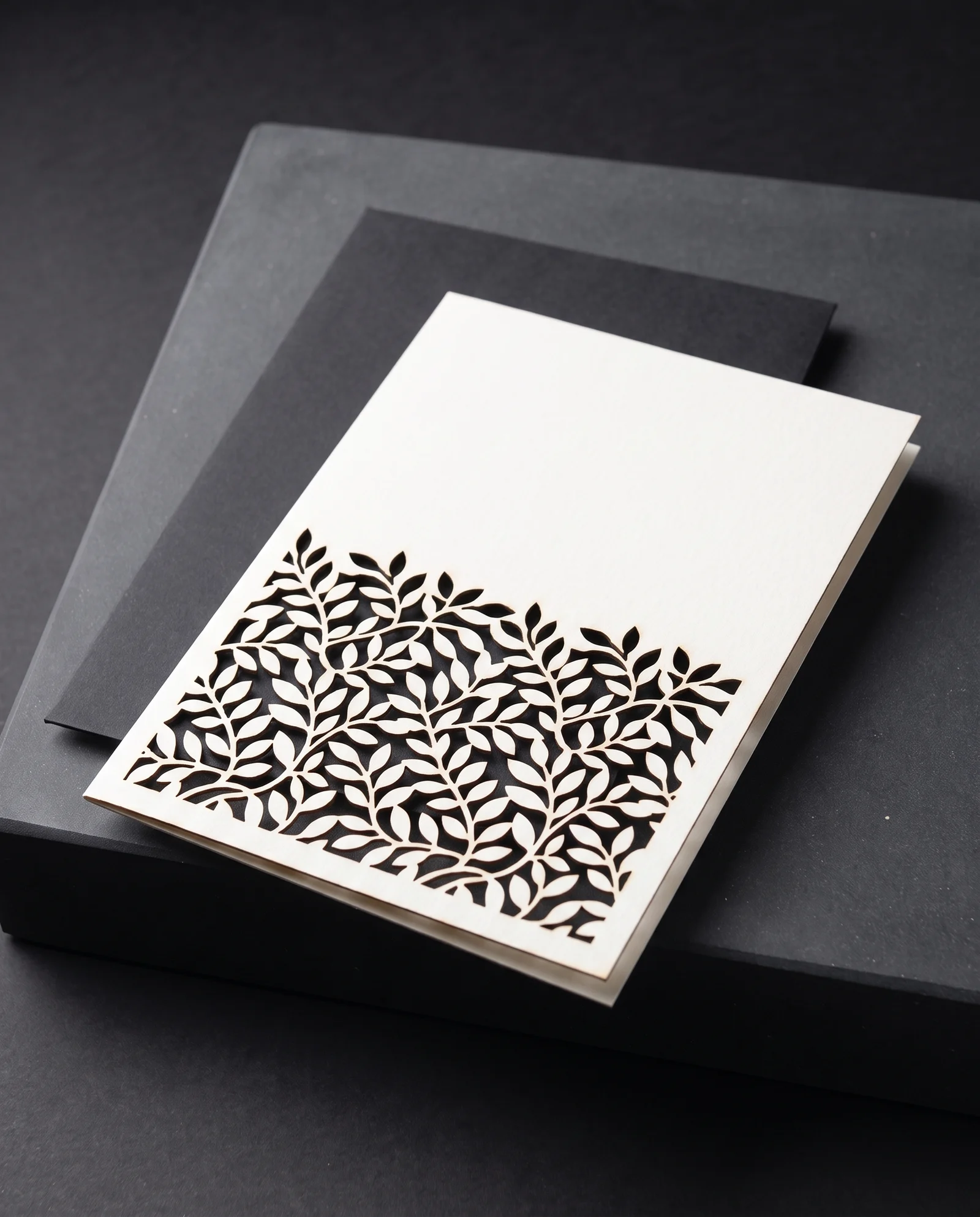 Fine botanical laser cutting in cream cotton over black card.