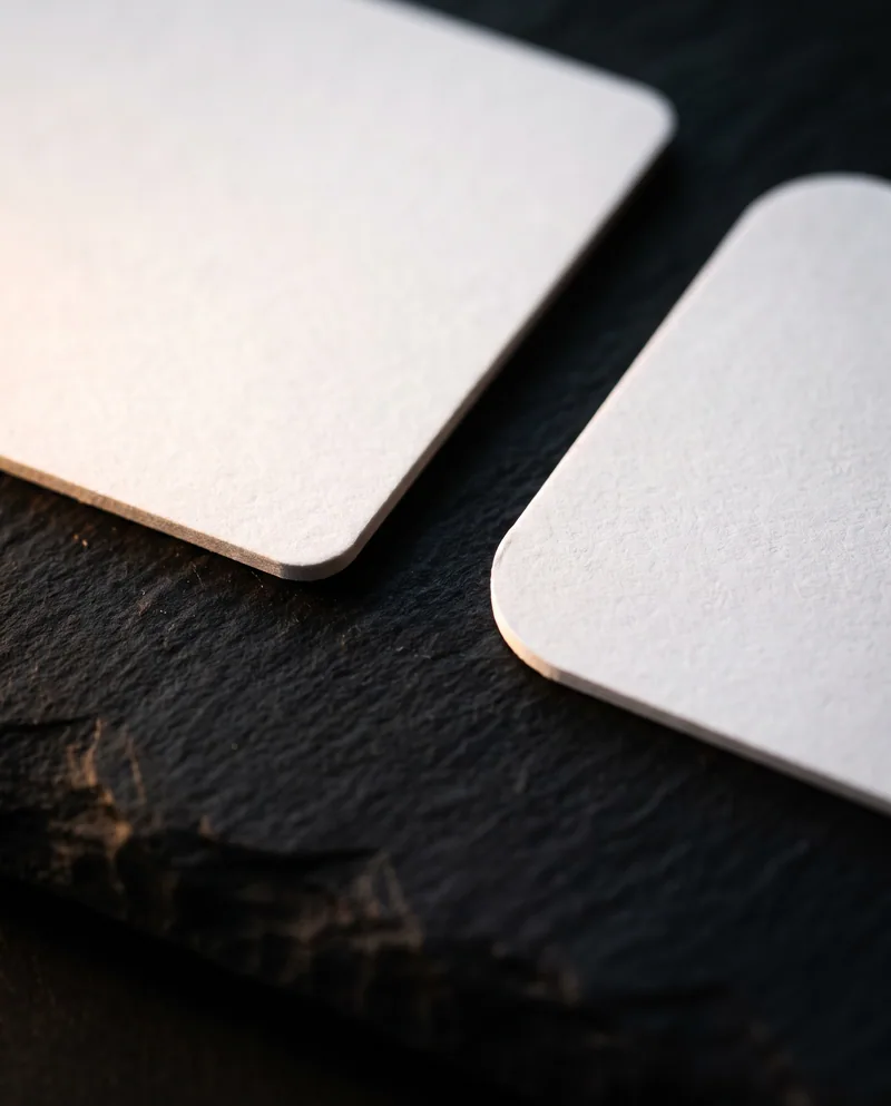 Macro of white business card corners comparing 1/8 inch and 1/4 inch radius on stone