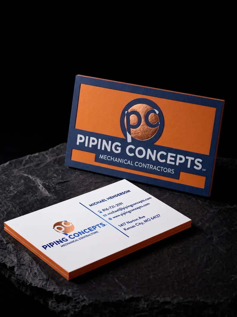 Three-layer business card with an orange middle layer visible along the edge and copper foil on blue