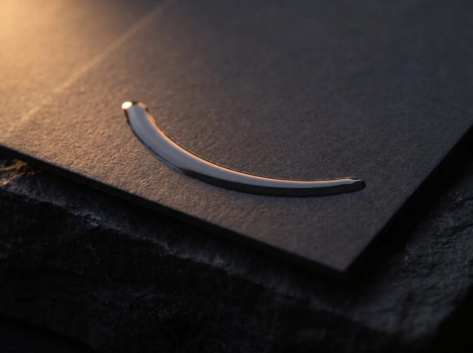 Macro of raised clear spot UV ridge standing proud of charcoal soft-touch velvet card surface