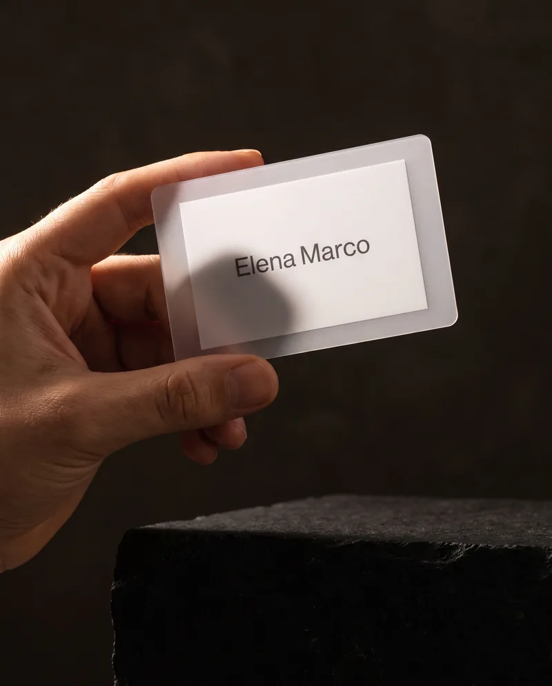 Hand holding a frosted plastic business card with white flood panel against warm light
