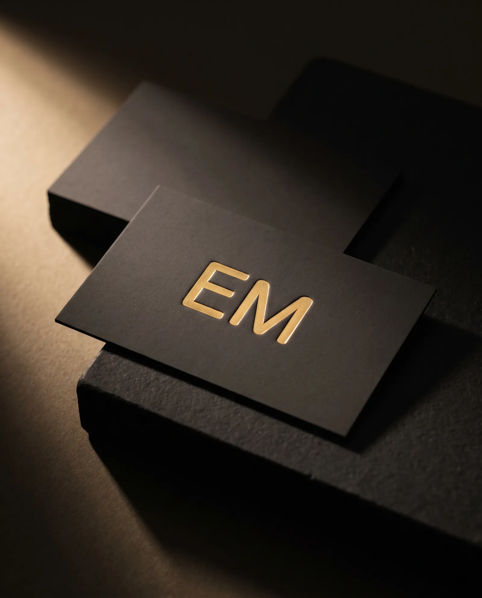 Charcoal soft-touch business card with a raised gold foil monogram