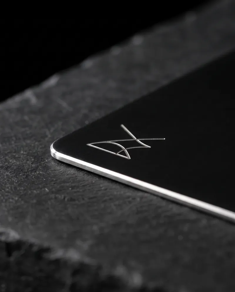 Macro of a metal business card corner: polished edge and an engraved logo