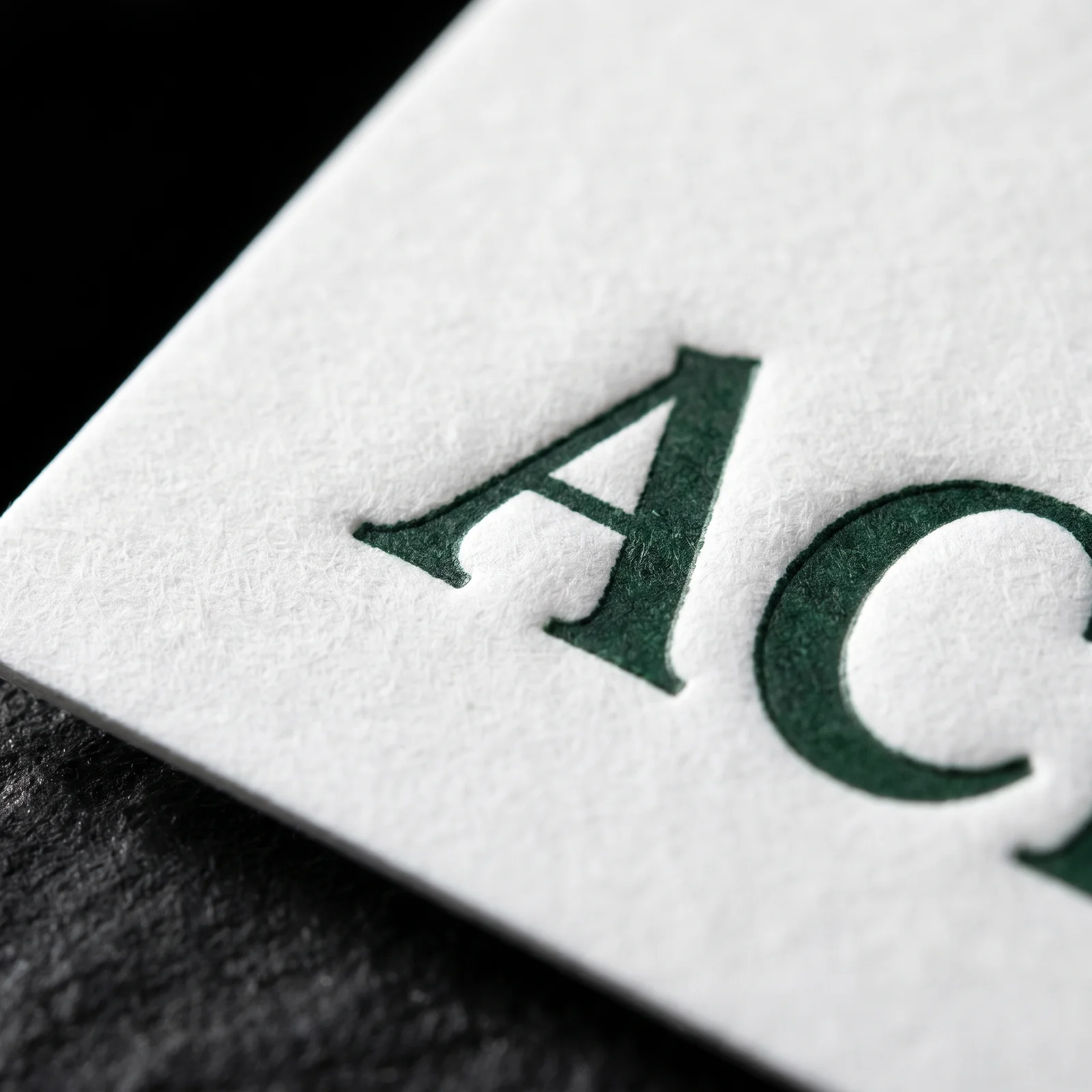 Close-up of letterpress lettering pressed into soft white cotton paper