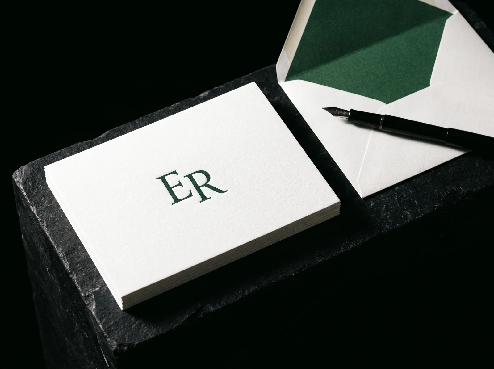 Monogrammed note cards with a letterpress "ER" monogram in forest green on white cotton, with green-lined envelopes and a fountain pen
