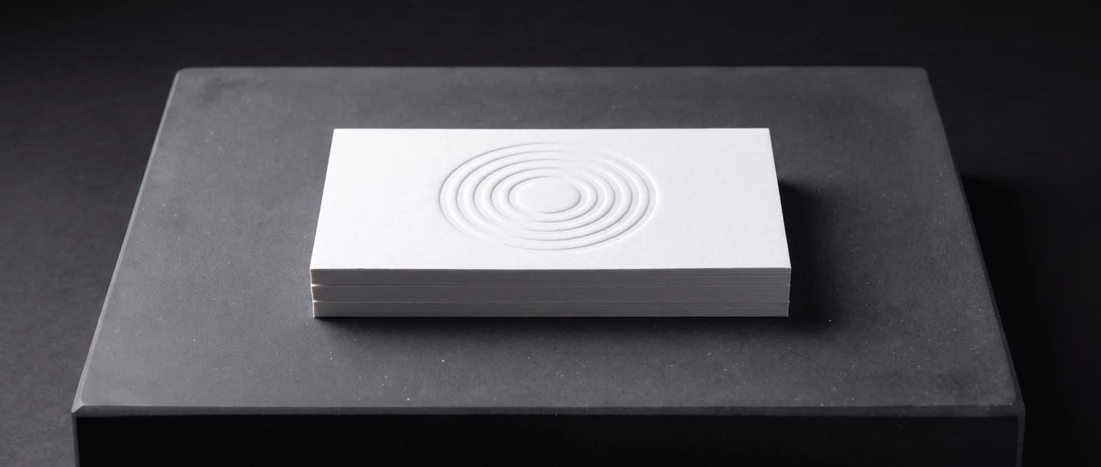 A deep blind deboss in thick white cotton, visible only as shadow.