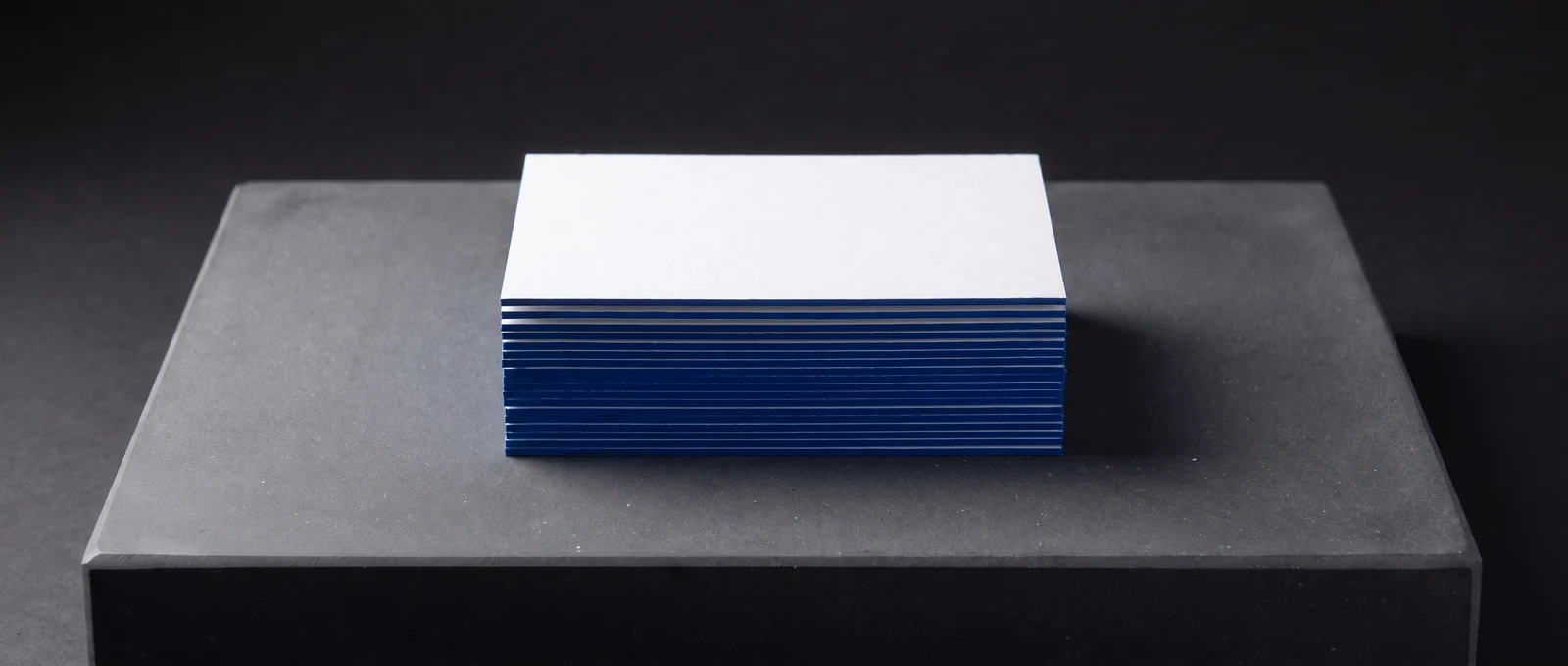 A stack of white cards with a solid cobalt-blue painted edge.