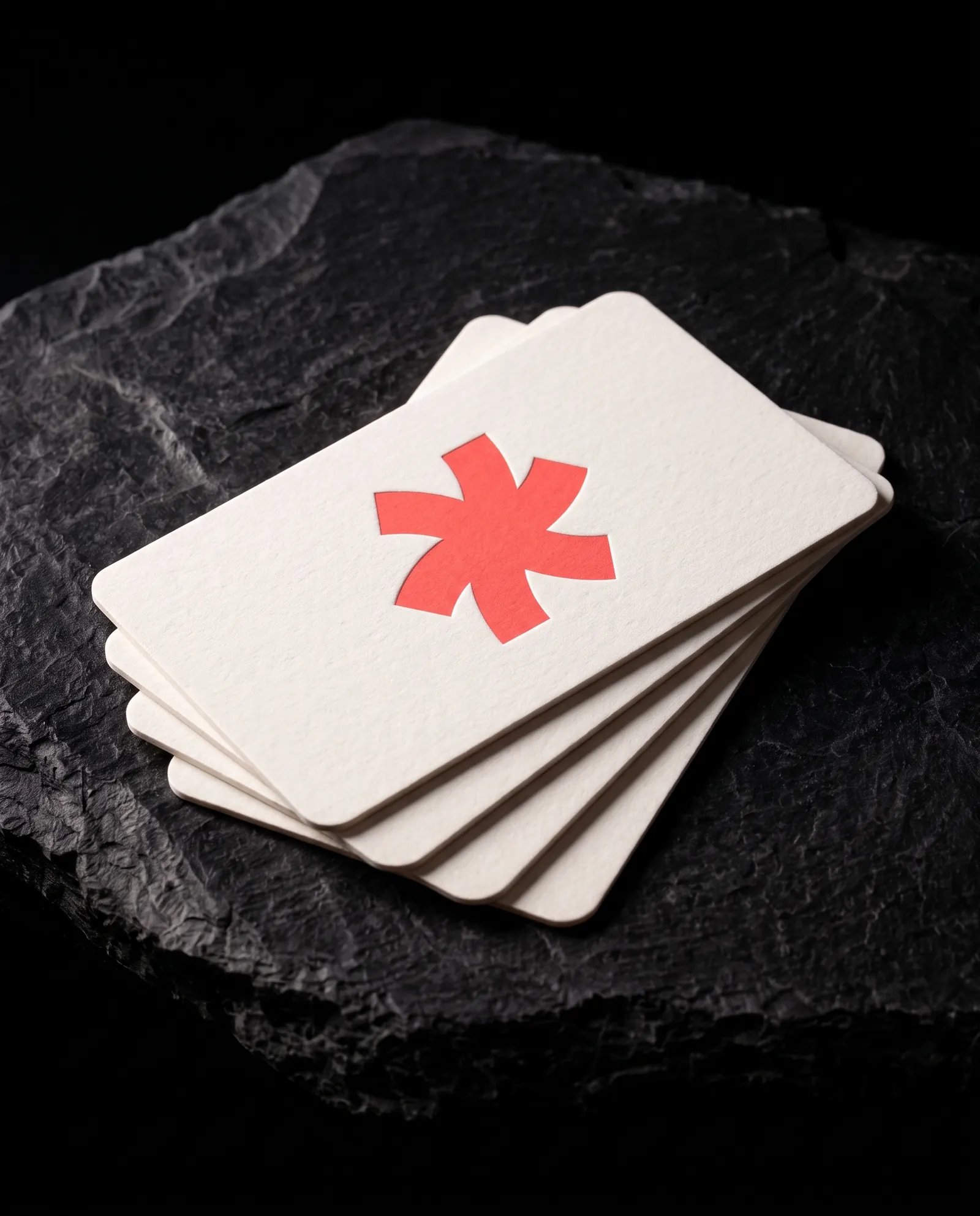 Fanned stack of white rounded-corner business cards with a coral Print Peppermint mark, the light catching the soft radius on every corner