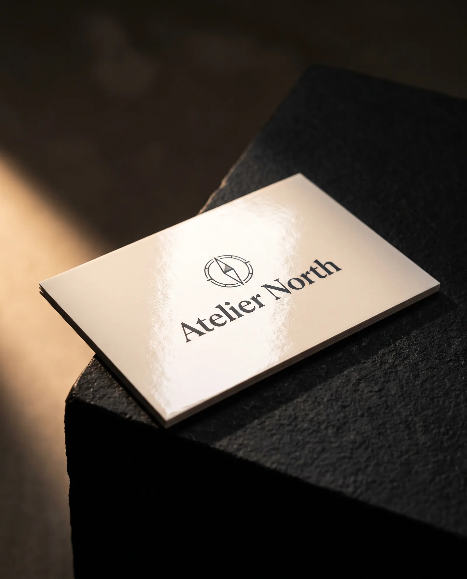 Concept rendering of a glossy off-white business card with charcoal wordmark and bright highlight