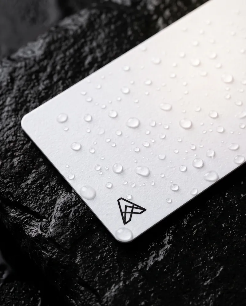 White plastic business card with water droplets on wet stone