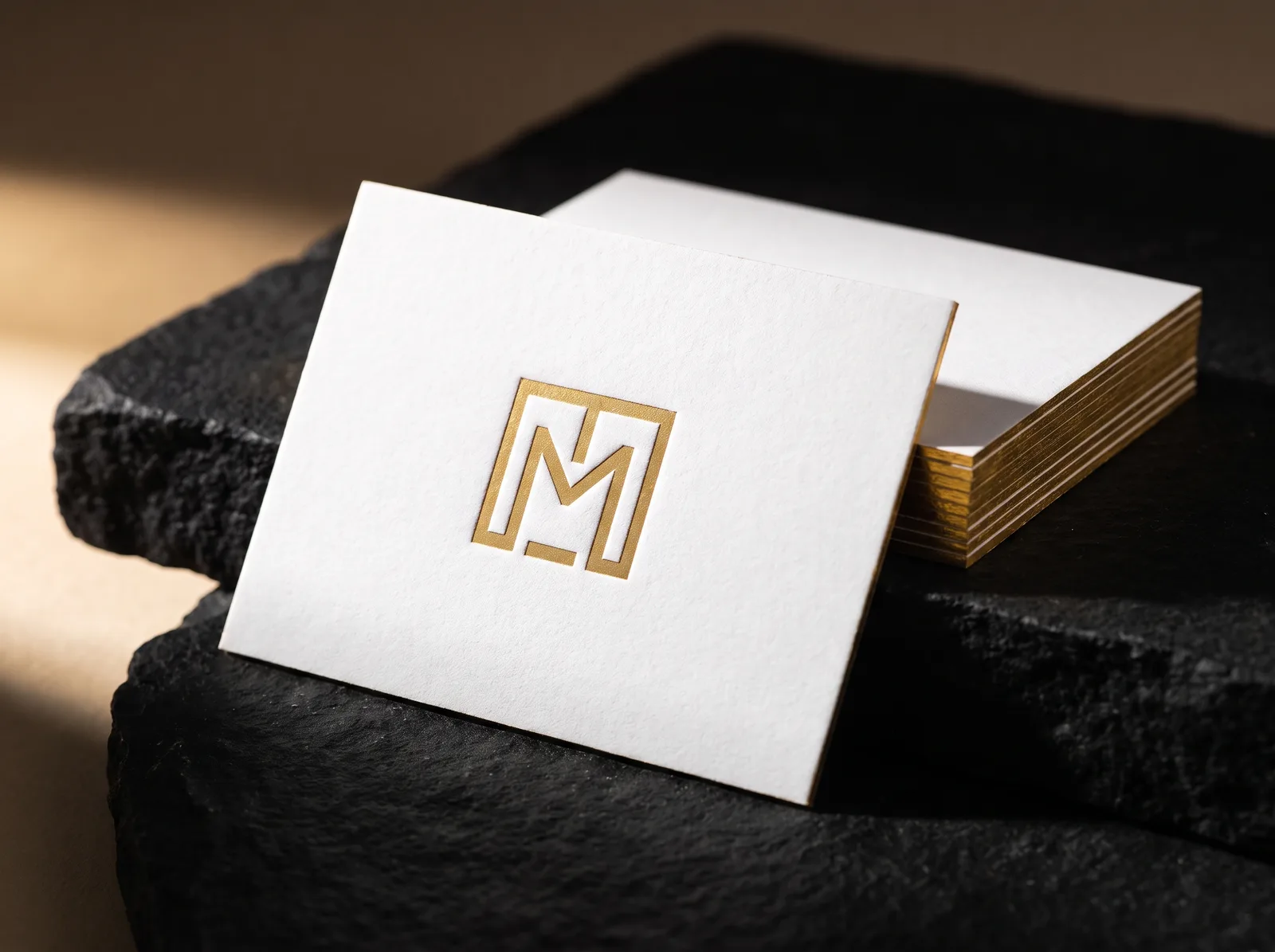 Debossed business card with gold foil in the impression and gold foiled edges on square corners