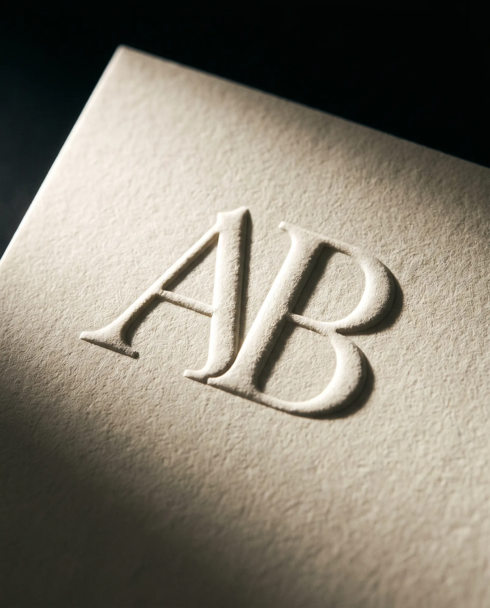 Blind embossed monogram on ecru cotton under side light.