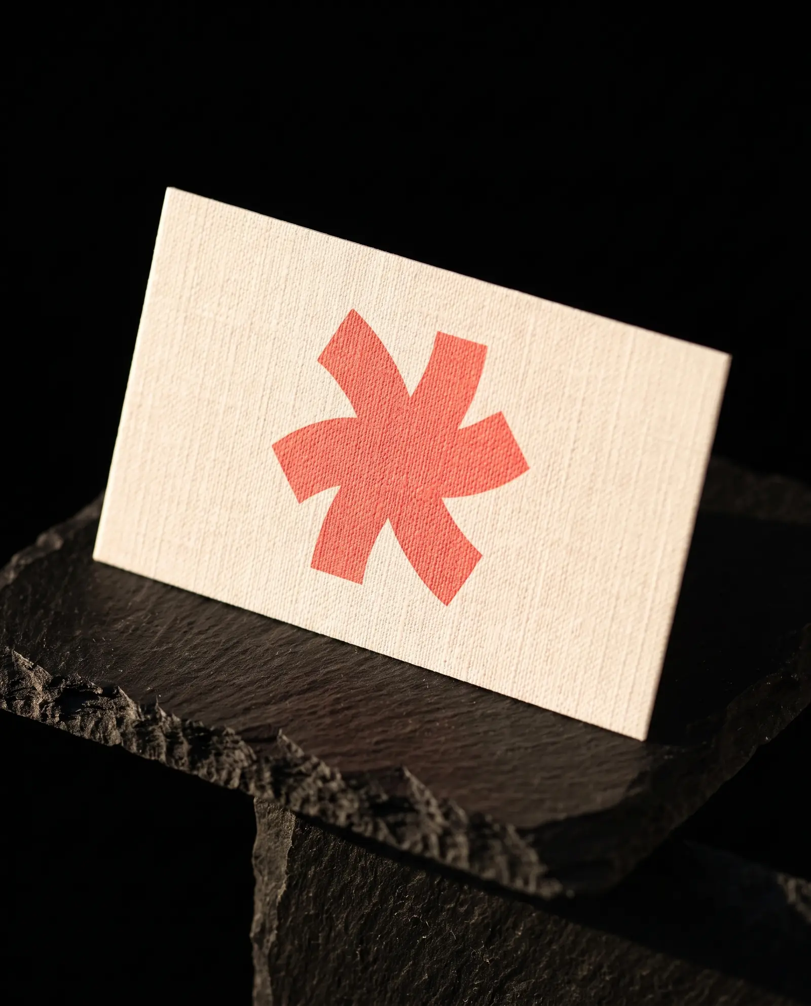Natural linen-textured business card with a coral Print Peppermint mark, the woven crosshatch visible under raking light