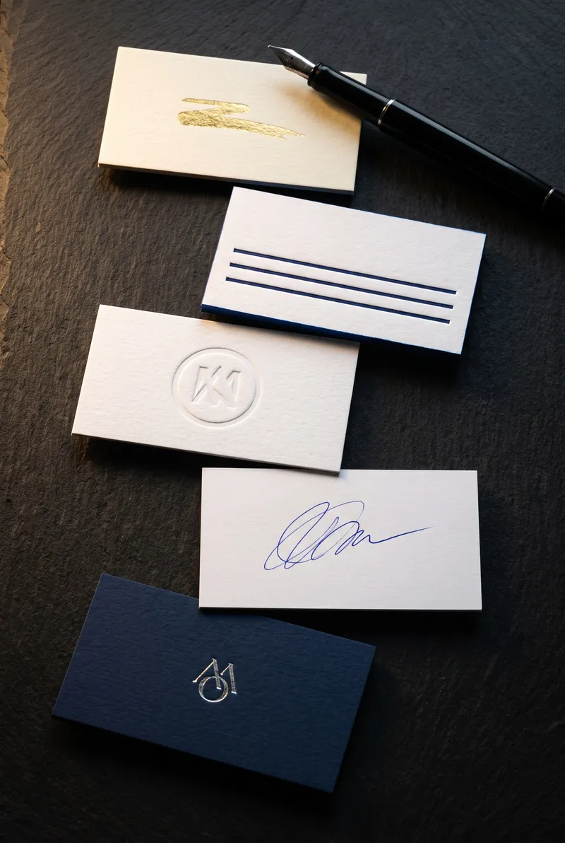 Overhead flat lay of five notary business cards: foil, letterpress, emboss, write-on, navy silver foil