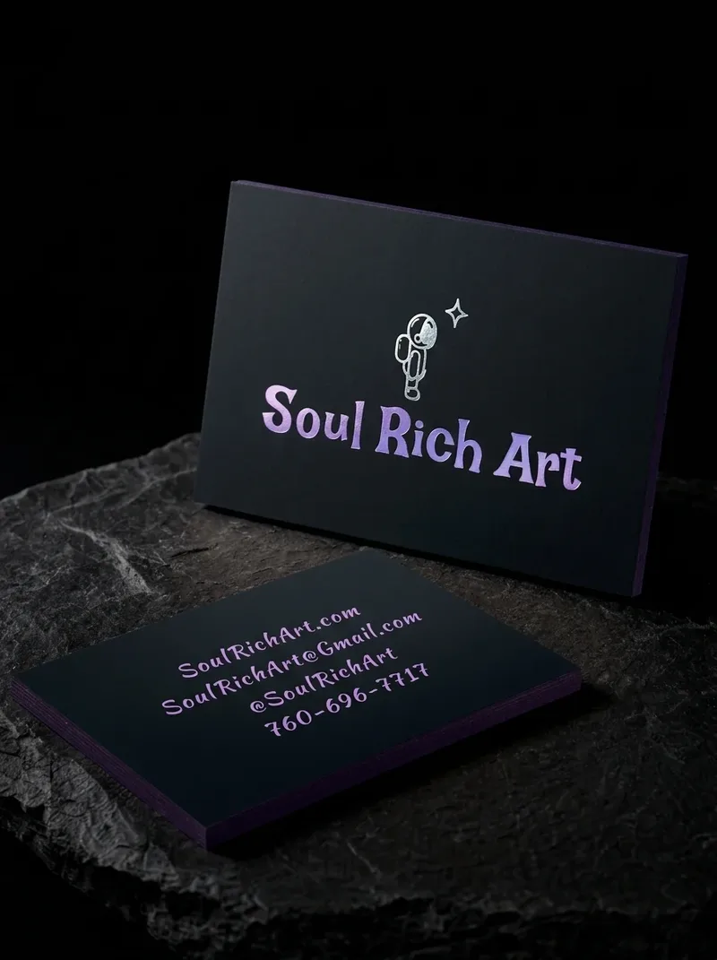 Illustrator business card with a small astronaut drawing in silver foil and a lavender foil wordmark on black