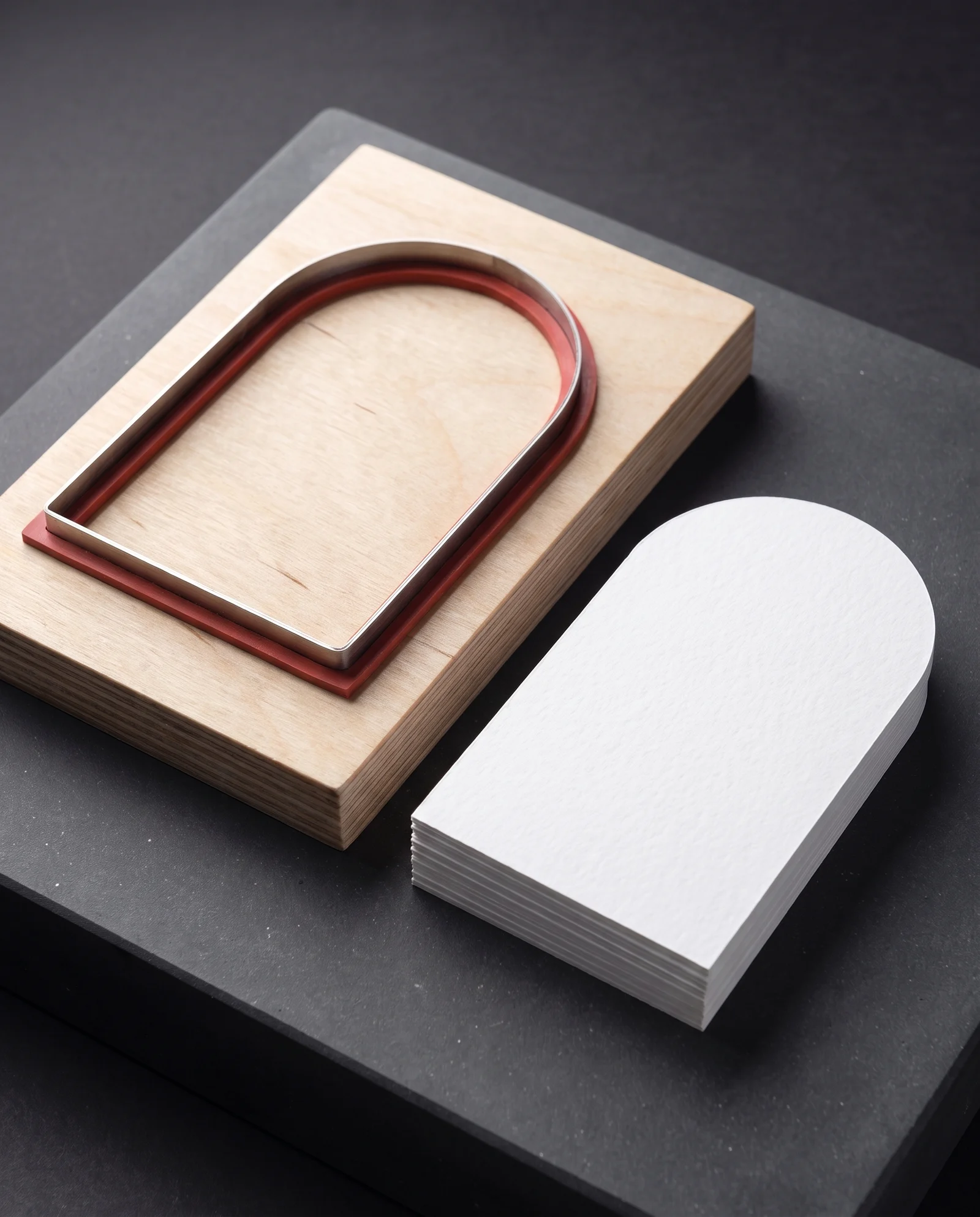 A steel-rule die beside the arch-shaped cotton cards it cut.