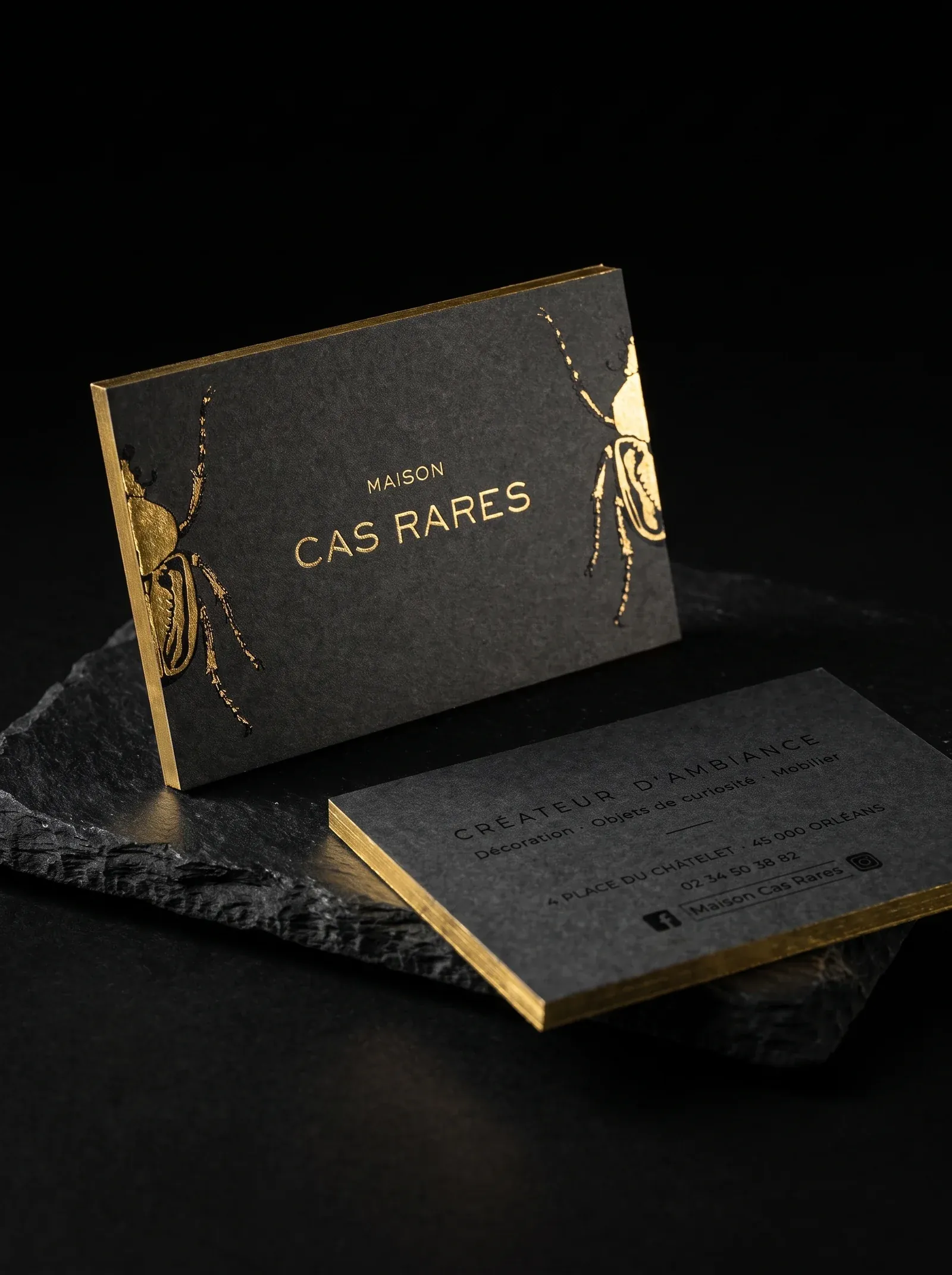 Maison Cas Rares business cards: gold foil beetles and a gold foil edge on charcoal stock, on black stone