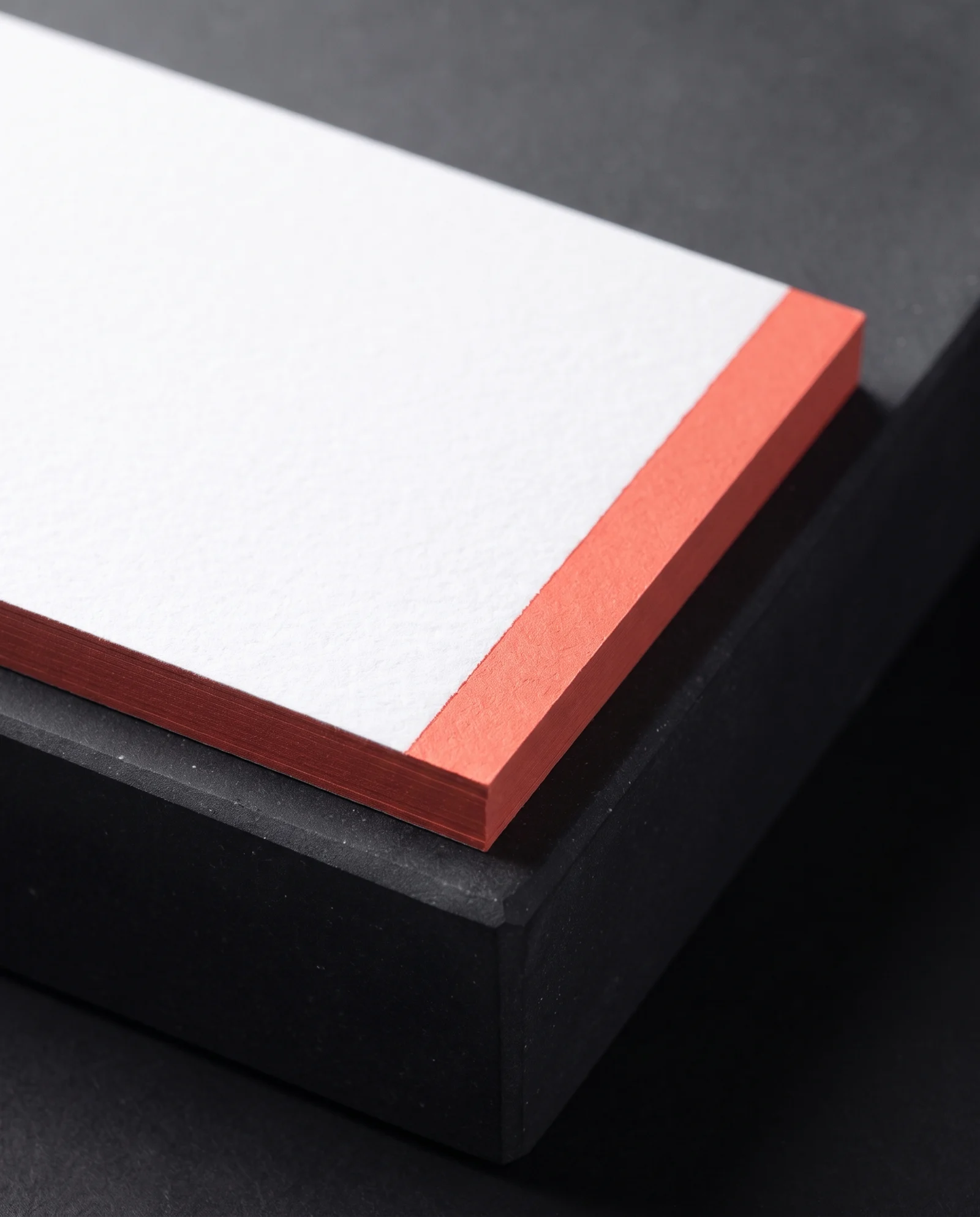Macro of a coral painted edge stopping cleanly at the card face.