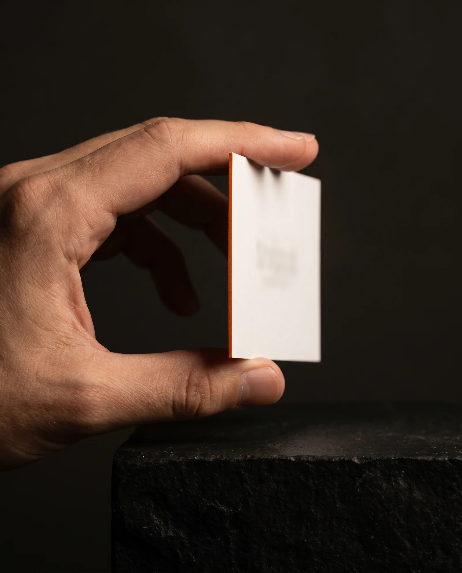 Hand holding a thick business card edge-on so the colored edge shows