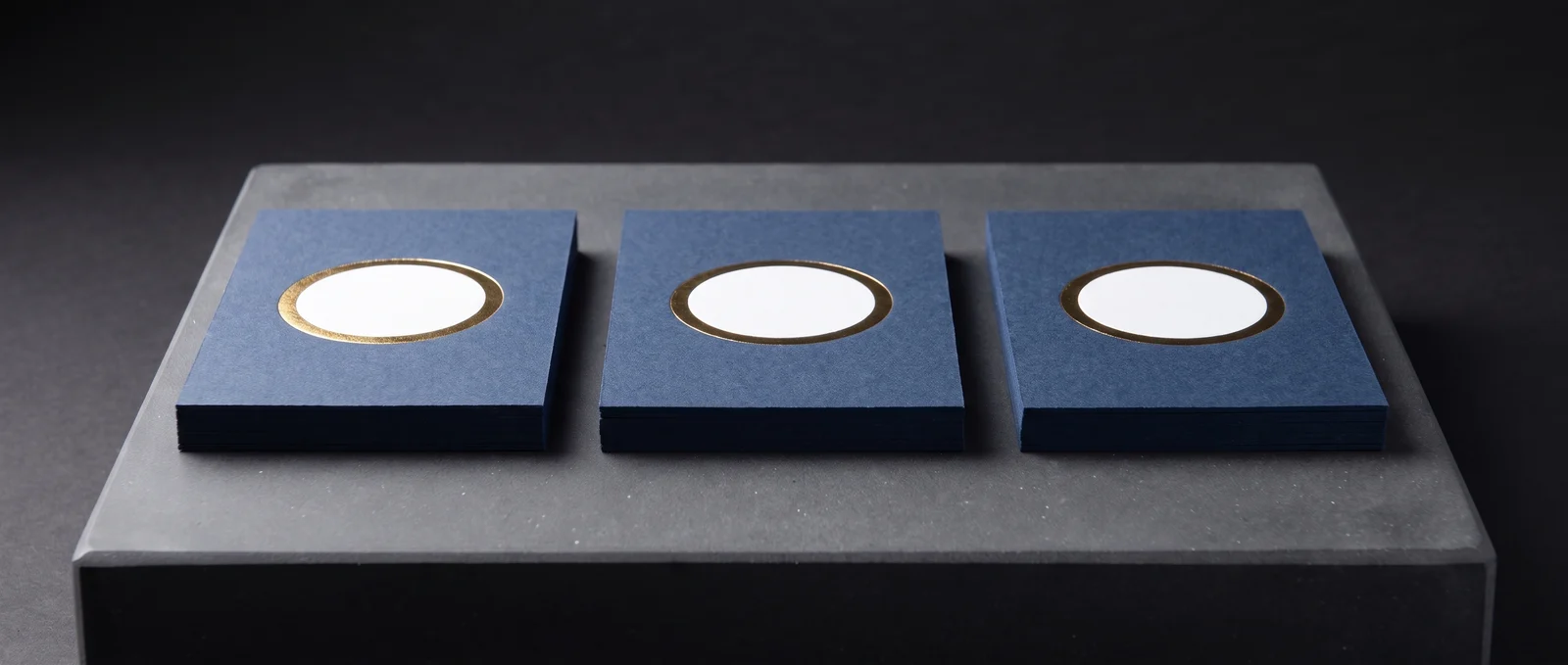 Navy cards with a white foil disc and a gold foil ring stamped over it.