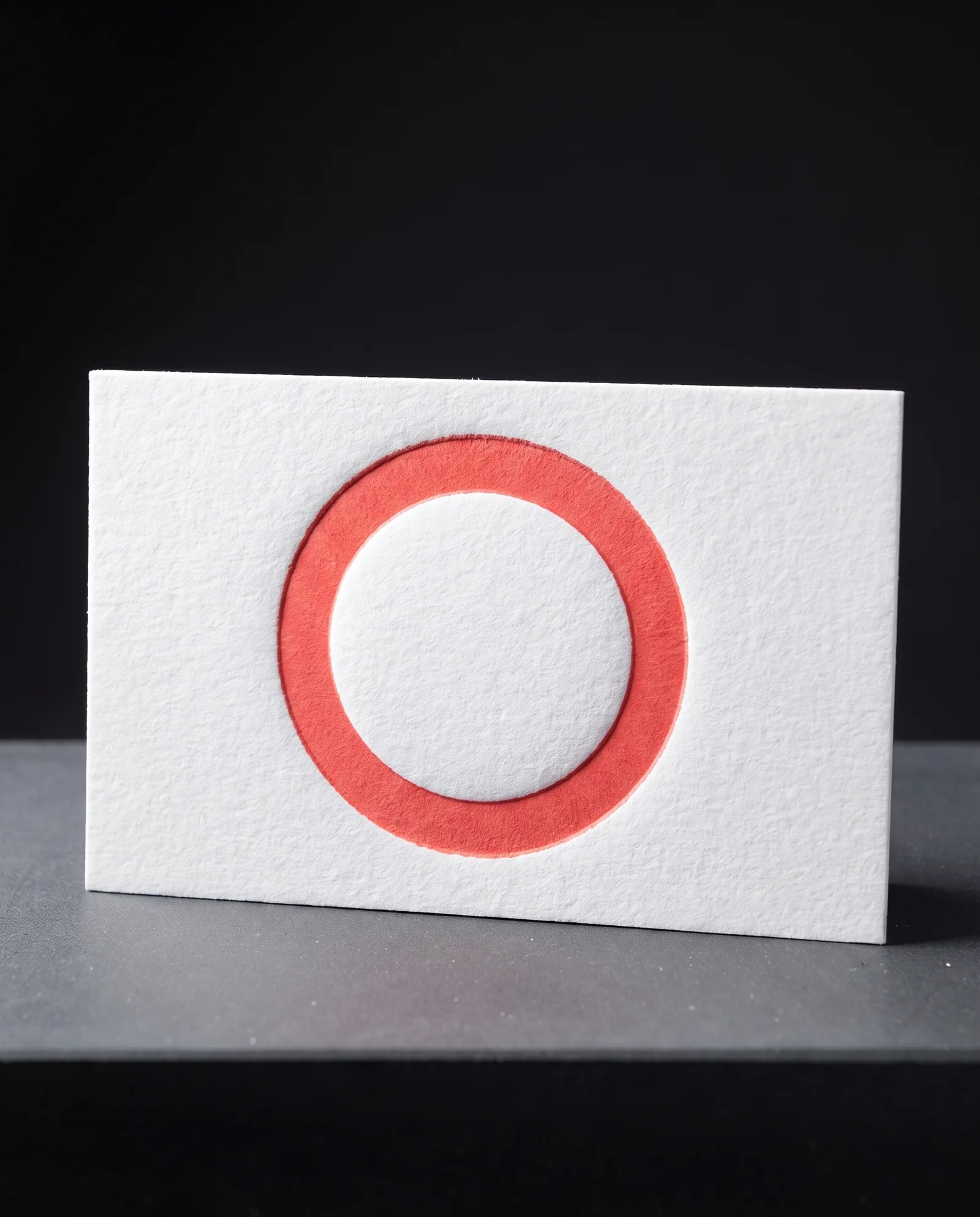 Coral letterpress ink inside a deep impression in cotton.