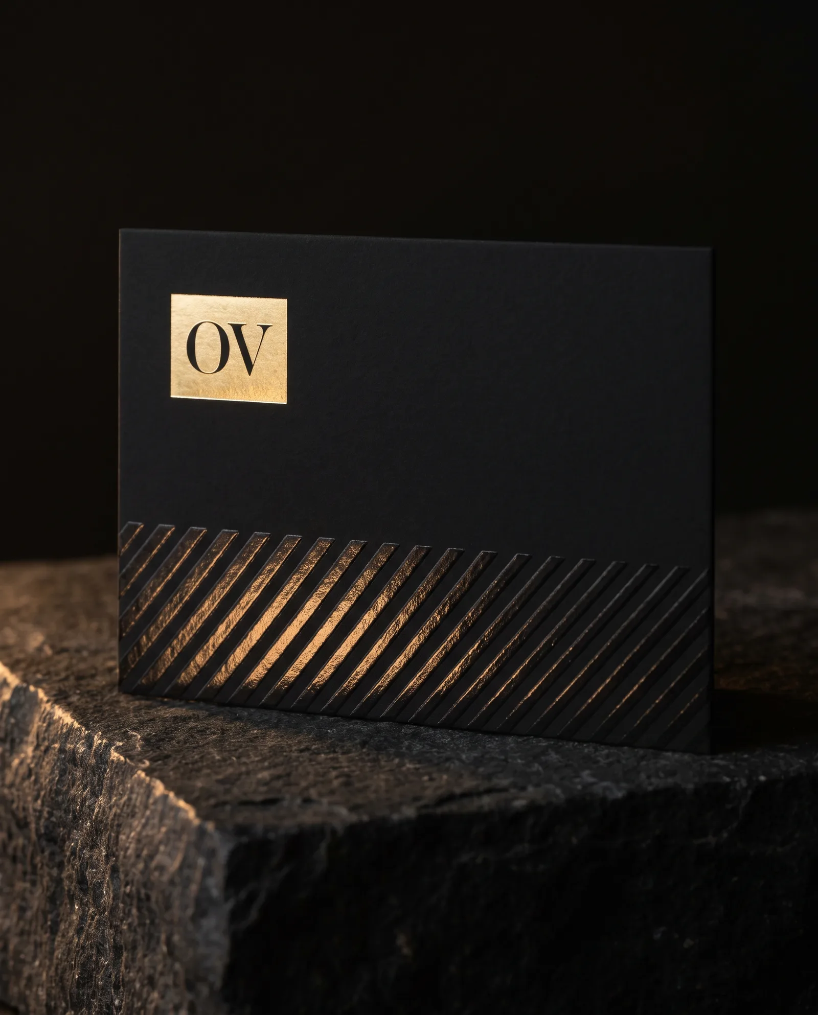 Black soft-touch business card with gold foil monogram and separate clear spot UV diagonal lines